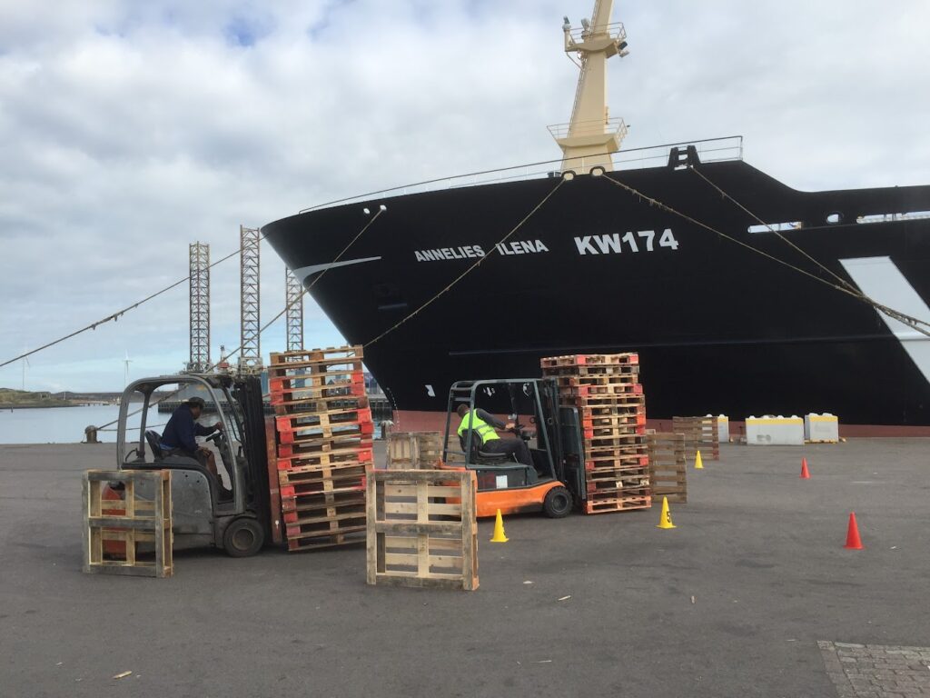 Heftruck aan het werk in de haven naast een schip tijdens een combinatieopleiding