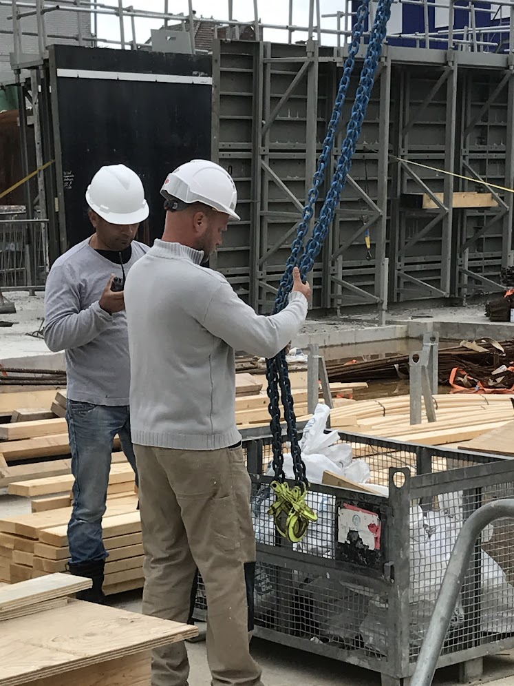 Medewerker slaat een last aan op een bouwplaats tijdens de herinstructie veilig hijsen